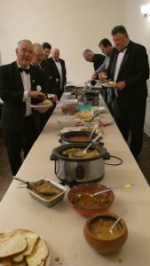 Lodge Members serving themselves curry from a long table